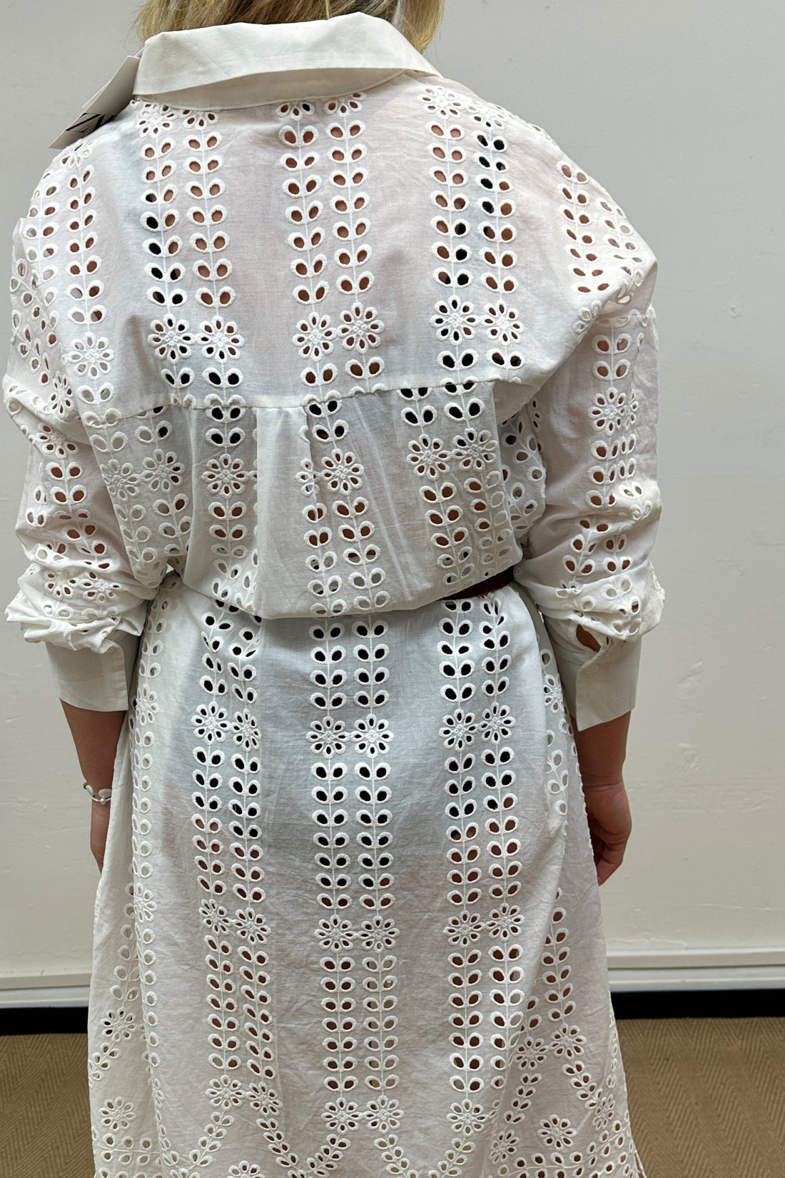 White eyelet dress worn by a person against a plain background